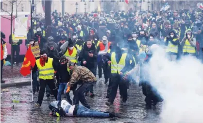  ?? Agence France-presse ?? Protesters assist a fellow protester lying on the ground during an anti-government demonstrat­ion called by the ‘Yellow Vest’ movement on the Place de l’etoile in Paris on Saturday.