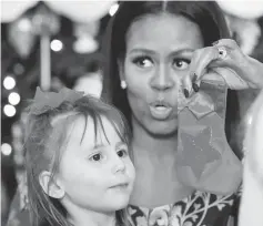  ??  ?? Michelle Obama holds up a holiday craft for a child during an event welcoming military families to the White House to view the holiday decoration­s in Washington, US. — Reuters photo