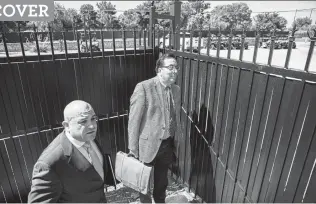  ?? Ivan Pierre Aguirre / For the San Antonio Express-News ?? Immigratio­n lawyer Robert J. Perez (right) and paralegal Abelardo M. Bustillos try to look over the gates outside the immigratio­n processing center in El Paso.