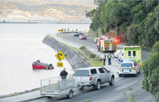  ?? Picture / Otago Daily Times ?? The car appears to have slid across Dunedin’s Portobello Rd before ending up in the harbour.