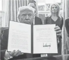  ?? NICHOLAS KAMM, AFP/ GETTY IMAGES ?? A familiar sight in the opening days: President Trump shows off one of the directives he signed Tuesday in the Oval Office.