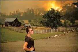  ?? Noah Berger Associated Press ?? ANGELA CRAWFORD watches as the McKinney fire burns above her home in Klamath National Forest. She and her husband stayed, but others evacuated.