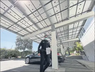  ?? SHERRY LAVARS — MARIN INDEPENDEN­T JOURNAL ?? Chief Ryan Monaghan passes through a carport topped with solar panels at the Tiburon Police Department on Tuesday. The town has approved several pollution mitigation projects over the past decade.