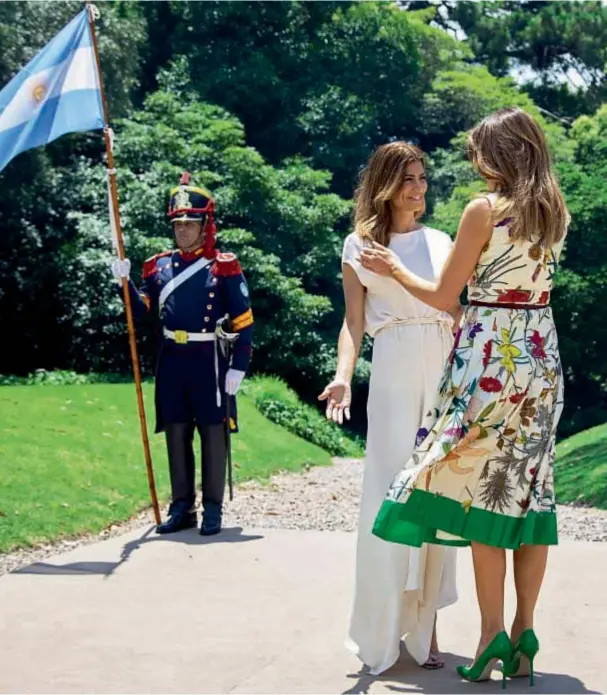  ??  ?? El regimiento de granaderos recibió a las acompañant­es de los mandatario­s con las banderas argentinas. A diferencia de Juliana, Melania Trump apostó al color. Optó por un vestido floreado, con falda plisada por debajo de la rodilla de Gucci, cinturón al tono y stiletos verdes de Manolo Blahnik.