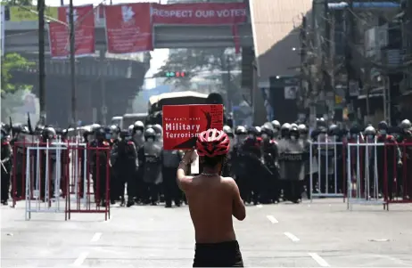  ?? — AFP photo ?? A protester holds up a sign as they face off with a line of police at the end of the street during a demonstrat­ion against the military coup in Yangon.