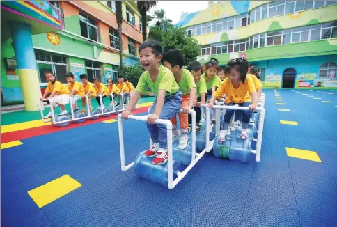  ?? WANG HU / XINHUA ?? Children in Hubei province compete on toy trains made of discarded water containers to promote green awareness.