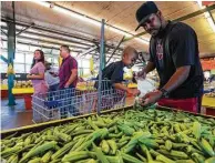  ??  ?? Greg Turner and his son, Johnny, pick okra out of a bin at Canino Produce. A local group has an agreement to acquire the Farmers Marketing Associatio­n of Houston.