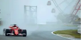  ??  ?? Diluvio La Ferrari di Sebastian Vettel sotto il nubifragio di Suzuka: le seconde prove libere sono state accorciate di 45 minuti (LaPresse)