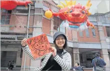  ?? Picture: AP ?? A woman holds a spring couplet with dragon patterns that she drew herself for the upcoming Lunar New Year celebratio­ns at the Dihua street market in Taipei, Taiwan, Thursday, February 8, 2024.