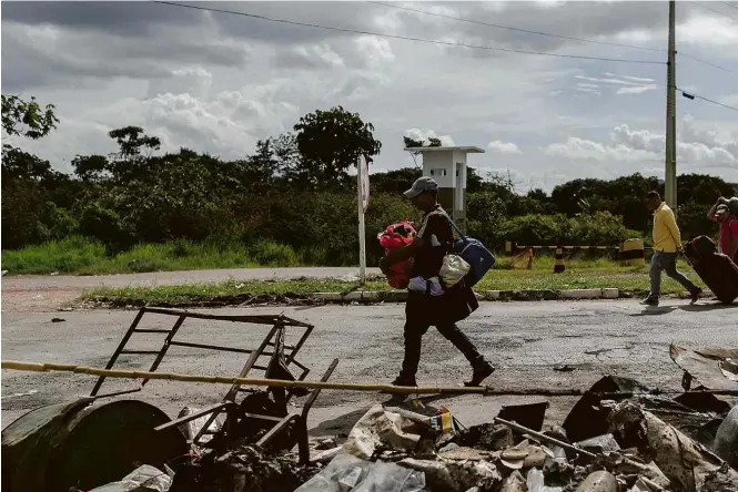  ??  ?? Venezuelan­o caminha por Pacaraima, em Roraima, após conflito entre refugiados e brasileiro­s na véspera
