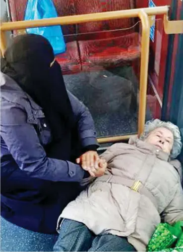  ??  ?? Compassion: The Muslim woman holds the 84-year-old’s hand after she fell on a bus