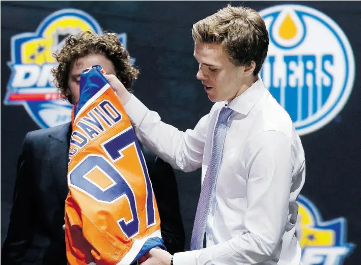  ?? Alan Diaz/The Associat ed Press ?? Connor McDavid prepares to put on an Edmonton Oilers sweater — with his No. 97 — after being picked first overall in the NHL entry draft on Friday at Sunrise, Fla.