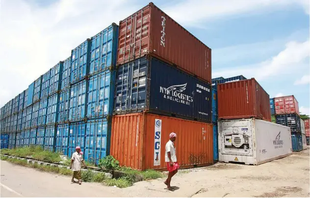  ?? File/reuters ?? ±
Workers walk past containers at a depot on Willingdon Island in the southern Indian city of Kochi.