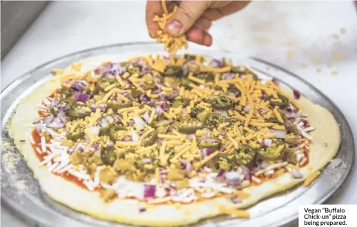  ??  ?? Vegan “Buffalo Chick-un” pizza being prepared.