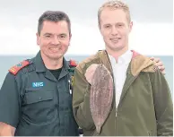  ??  ?? Sam Quilliam holds a larger version of the Dover sole that choked him. Matt Harrison, left, used forceps to pull the fish out of Sam’s throat