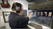  ?? MICHAEL WYKE - ASSOCIATED PRESS ?? Steve Naremore, founder and CEO of TuffyPacks, fires his Glock handgun into a backpack seven yards away containing one of his ballistic shields.