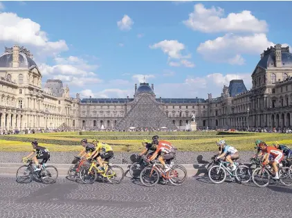  ?? LAURENT CIPRIANI/ASSOCIATED PRESS ?? Britain’s Chris Froome, wearing the overall leader’s yellow jersey, rides with the main pack in front of Paris’ Louvre Museum during Sunday’s final stage of the Tour de France. Froome coasted to his third win in four years.