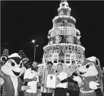  ??  ?? Malaysia Book of Records (MBOR) officer T Lavnesh (second left) presents certificat­e acknowledg­ing that the replica cake is the biggest in Malaysia, to A’Famosa Resort director Datuk Alex Lau (third right) on Friday night. The giant cake, which is 18.9...