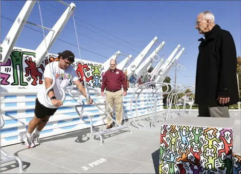  ?? ?? Allen Haring, Keith Haring’s father, right, and Kutztown University President Kenneth S. Hawkinson watch Chase Spencer, 20, a junior from Mays Landing, N.J., do a push-up variant on the rings during dedication ceremonies Friday at the Keith Haring Fitness Court on the campus of Kutztown University.