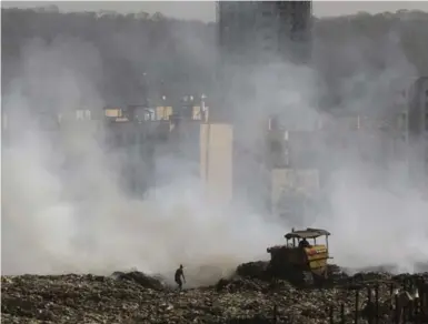  ?? SHAILESH ANDRADE/REUTERS ?? Smoke billows from the burning garbage at the Deonar dumping ground in Mumbai, while a rag picker seeks recyclable­s.
