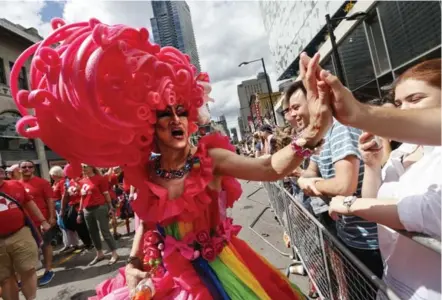  ?? BERNARD WEIL PHOTOS/TORONTO STAR ?? A marcher high-fives one of the thousands who lined Yonge St. for Sunday’s parade, which was largely free of the protests that marked last year’s event.