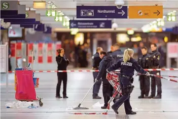  ?? FOTO: GAMBARINI/DPA ?? Polizisten entfernen nach dem Amoklauf im Düsseldorf­er Hauptbahnh­of Absperrbän­der.