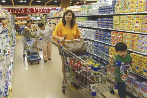  ?? ALAMY ?? A mother and her son are seen walking past aisles of milk at a grocery store in Metro Manila.