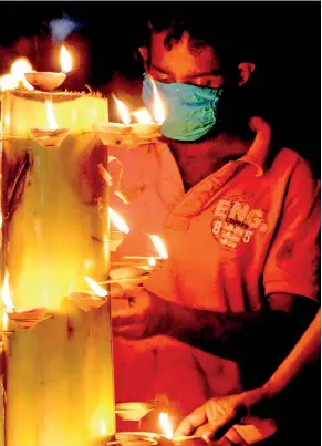  ??  ?? Humble little clay lamps spread light: Residents of Valmailla, Bandaragam­a light pahan in front of the temple. Pix by Indika Handuwala