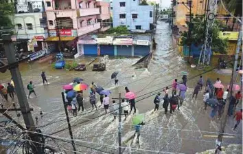  ?? PTI ?? People stand on flooded streets after overnight rains in Hyderabad yesterday. Meteorolog­ical Department officials have warned of more heavy rains in Telangana over the next 48 hours.