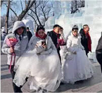  ??  ?? Couples walk past an ice sculpture before a group wedding.