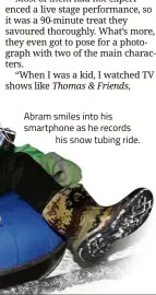  ??  ?? Abram smiles into his smartphone as he recordshis snow tubing ride.