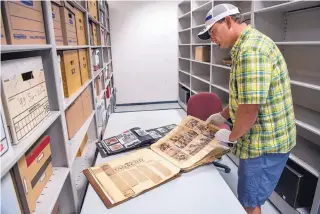  ?? COURTESY OF THE INSTITUTE OF AMERICAN INDIAN ARTS EDDIE MOORE/JOURNAL ?? Ryan Flahive, archivist for Institute of American Indian Arts, looks through a scrapbook kept by the late artist Pop Chalee. The school has received a grant to restore and preserve the Chalee items.