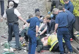  ?? Stefan Rousseau Press Assn. ?? BRITISH lawmaker Tobias Ellwood, center, helps a victim of the attack in London. Ellwood administer­ed CPR to the police officer who was stabbed, to no avail.