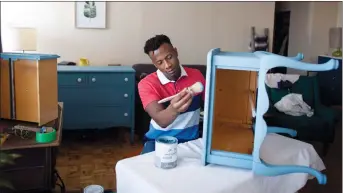  ?? THE CANADIAN PRESS/PETER POWER ?? Kbre Hamilton, who runs an online business selling antique furniture, refinishes a table in his Hamilton apartment on May 17.