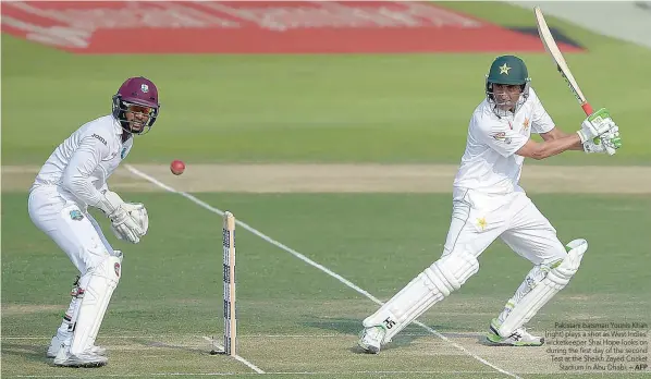  ?? — AFP ?? Pakistani batsman Younis Khan (right) plays a shot as West Indies’ wicketkeep­er Shai Hope looks on during the first day of the second Test at the Sheikh Zayed Cricket Stadium in Abu Dhabi.