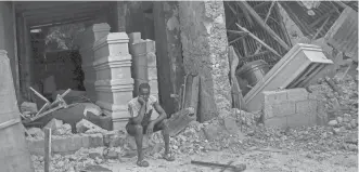  ?? MATIAS DELACROIX/AP ?? A man sits in front of a collapsed funeral home in Les Cayes, Haiti, on Monday, two days after a 7.2-magnitude earthquake struck the southweste­rn part of the country.