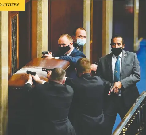  ?? ANDREW HARNIK / AP PHOTO ?? U.S. Capitol police with guns drawn stand near a barricaded door as protesters try to break into the House Chamber at the U.S. Capitol on Wednesday in Washington, D.C.