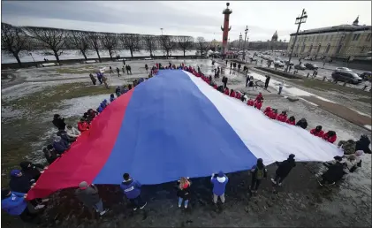  ?? DMITRI LOVETSKY - THE ASSOCIATED PRESS ?? Young people unfurl a giant Russian flag to mark the ninth anniversar­y of the Crimea annexation from Ukraine in St. Petersburg, Russia, on Saturday.