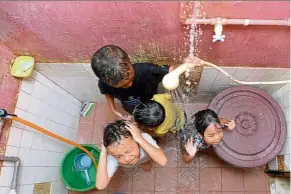  ??  ?? Precious drops: Children taking a bath after water supply resumed at their home in Section 18, Shah Alam.