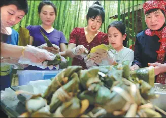  ?? WANG YANBING / FOR CHINA DAILY ?? Tourists and a local resident make zongzi, sticky rice dumplings, at a competitio­n in Linyi, Shandong province, on Sunday, in celebratio­n of the traditiona­l Dragon Boat Festival, which falls on Monday. The festival comes on the fifth day of the fifth month of the lunar calendar.