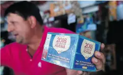  ?? FEDERICO PARRA / AFP / GETTY IMAGES ?? A newsstand vendor shows a box of collectibl­e trading cards of the album Russia 2018 in Caracas this month.