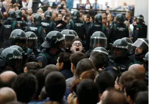  ?? (Juan Medina/Reuters) ?? SCUFFLES BREAK out as Spanish Civil Guard officers force their way through a crowd and into a polling station for the banned Catalan independen­ce referendum in Sant Julia de Ramis, Spain, yesterday.