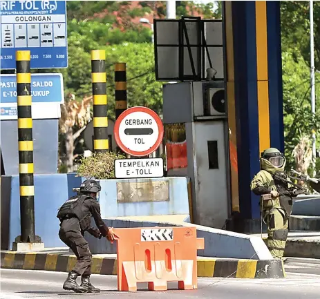  ?? BOY SLAMET/JAWA POS ?? DITUTUP SEMENTARA: Petugas mengamanka­n gerbang masuk tol Sidoarjo kemarin siang setelah ditemukan gulungan kertas dililit kabel mirip bom.