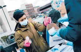  ?? JOSE A. ALVARADO JR./THE NEW YORK TIMES ?? New U.S. coronaviru­s cases have dropped by 21% in the last two weeks. Above, volunteers hand out face masks Monday in New York City.