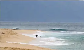  ??  ?? A surfer walks out of the ocean on Oahu’s north shore near Haleiwa. Encouragin­g people to stay away has severely damaged Hawaii’s economy, which relies heavily on the tourist dollar. Photograph: Caleb Jones/AP