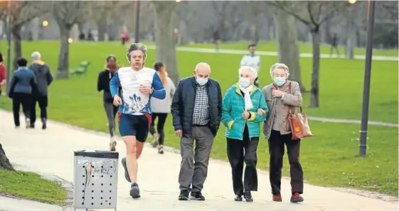  ??  ?? Un corredor practica deporte en la Vuelta del Castillo de Pamplona mientras tres ancianos pasean por la misma zona.