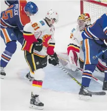  ?? DAVID BLOOM ?? Edmonton Oilers forward Tyler Pitlick, left, scores on Calgary Flames goaltender Jon Gillies, at right, while Flames defenceman Brett Kulak, centre, looks on during the third period of their pre-season game at Rogers Place in Edmonton on Monday.