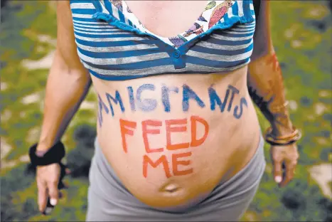 ?? ANDREW HARNIK/AP ?? A pregnant woman painted a message to farmworker­s as she joined a protest outside the White House to denounce President Donald Trump’s immigratio­n policies in 2017.