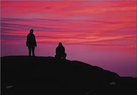  ?? SARAH GORDON/THE DAY ?? A couple watches the sunset from the rocks along Eastern Point in Groton on Thursday.