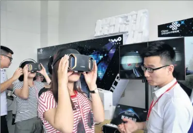  ?? LIANG SHENGJIAN / FOR CHINA DAILY ?? Customers try virtual reality devices at the China Unicom stand at a telecoms exhibition in Guangzhou, Guangdong province.